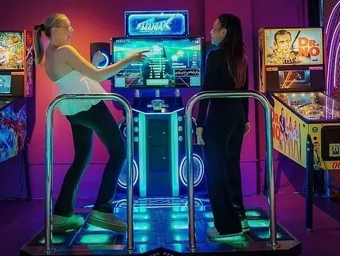 To personer spiller på en rytmebasert arkademaskin.