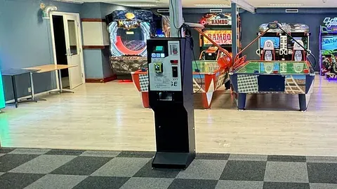 Betalingsterminal med spillmaskiner i bakgrunnen.