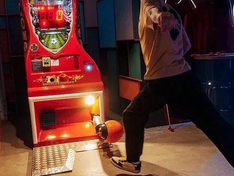 Person sparker til en fotball i en lysende arkademaskin.