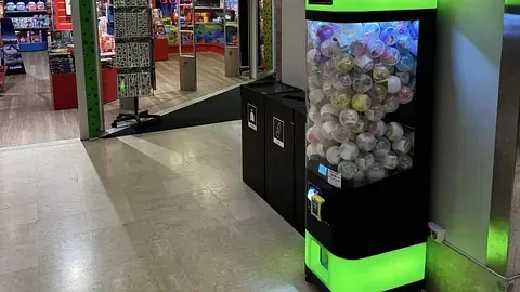 Spillmaskin med baller som premie og butikk i bakgrunnen.