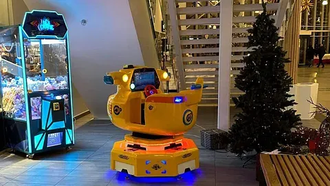 Gul barnekarusell med flymotiv ved juletre og trapp i senter.