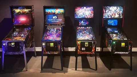 Fire flipperspill i mørk belysning med klassiske spilltemaer.