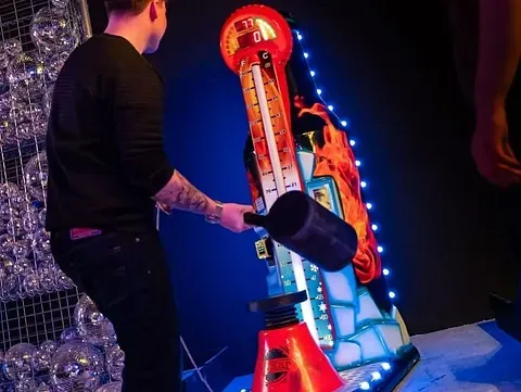 Mann med hammer spiller på en høy, lysende maskin.