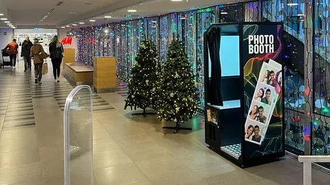 Fotoboks plassert i et kjøpesenter, med butikk i bakgrunnen.