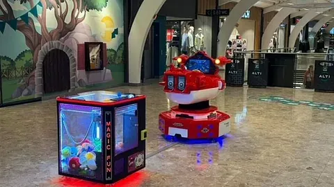 Rød barnekarusell står innendørs sammen med liten klyoautomat.